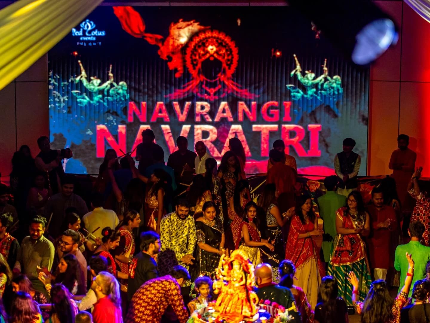 Navrangi Navratri by Red Lotus Events: a packed hall dancing garba beneath the festival's branded stage screen.